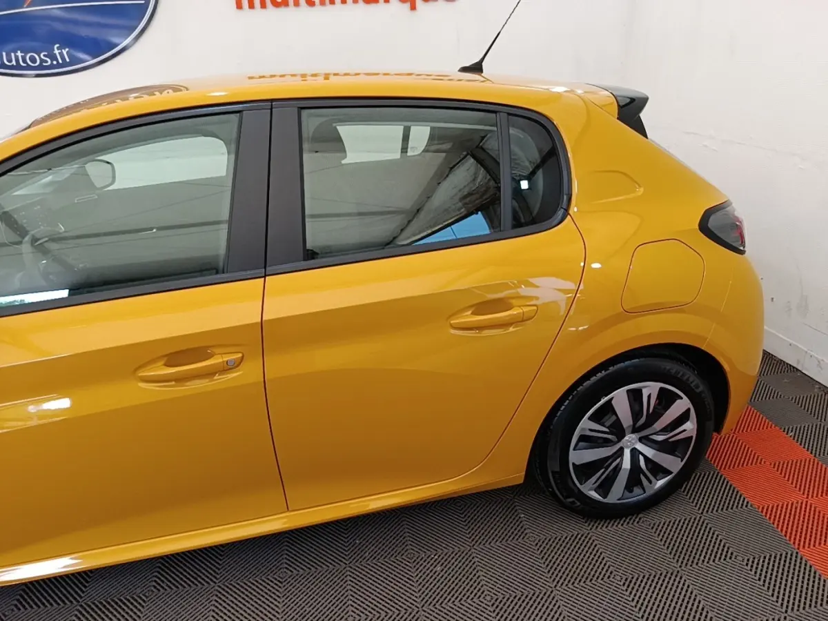 Vue latérale droite d'une Peugeot 208 jaune 2023 avec jantes alliage et poignées de porte ton caisse.