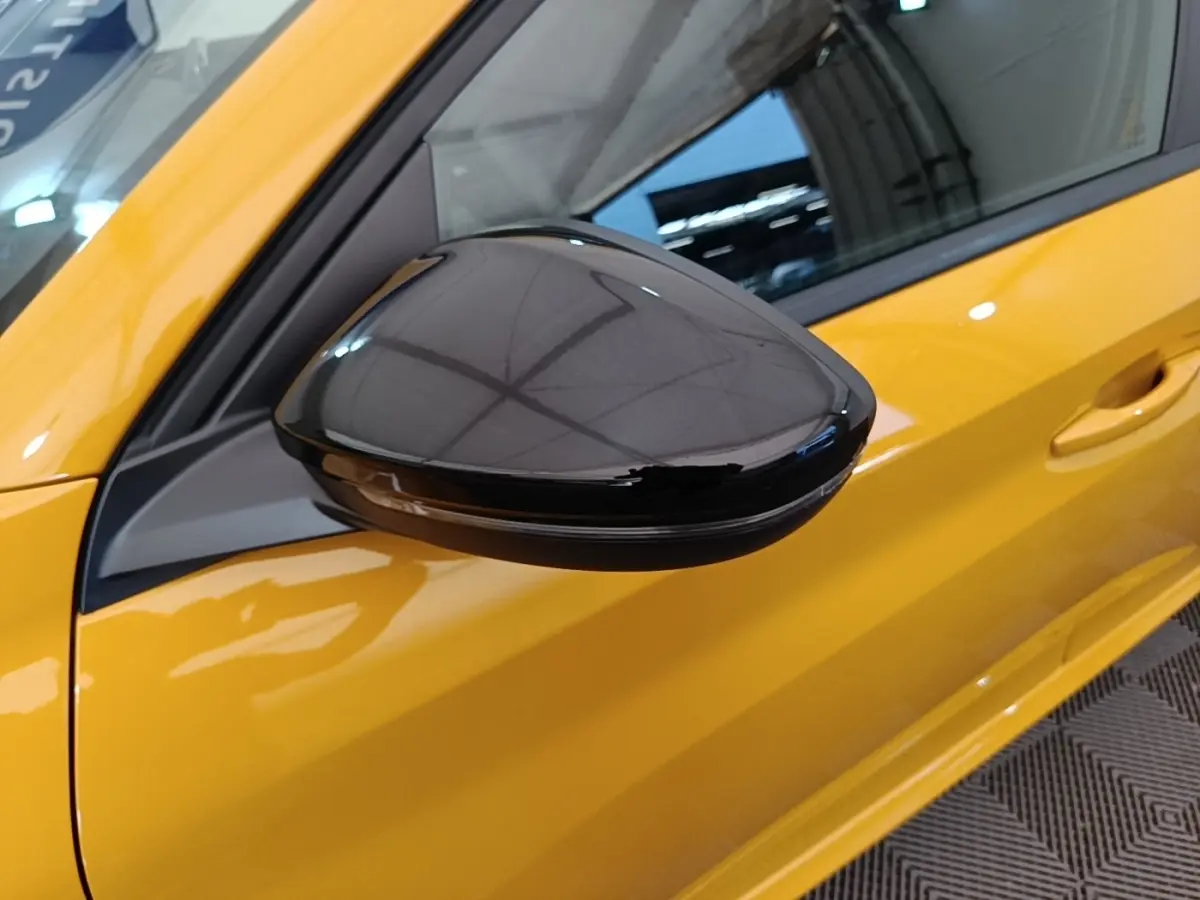Rétroviseur noir brillant côté gauche d’une Peugeot 208 jaune vue de près, avec poignée de porte visible.