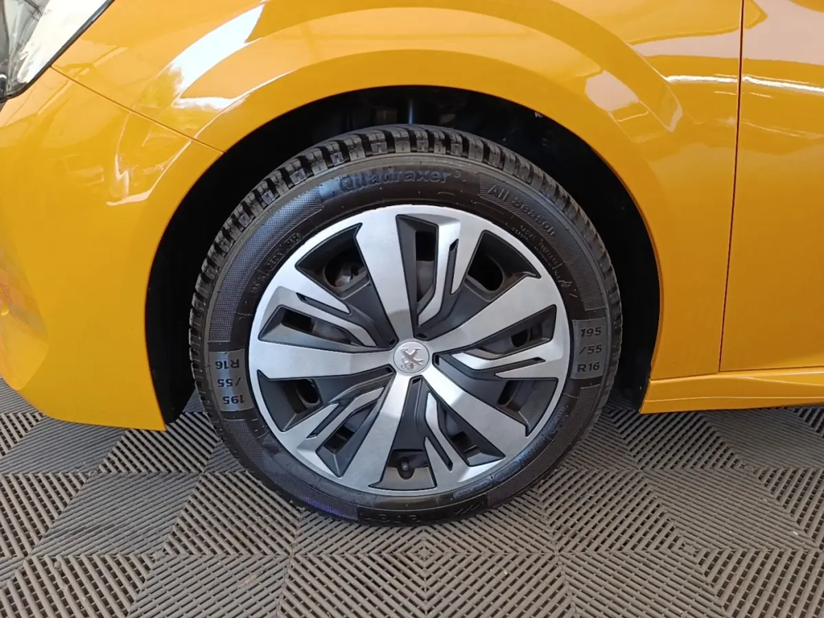 Gros plan sur la roue avant gauche de la Peugeot 208 jaune, mettant en valeur la jante design et la carrosserie brillante.