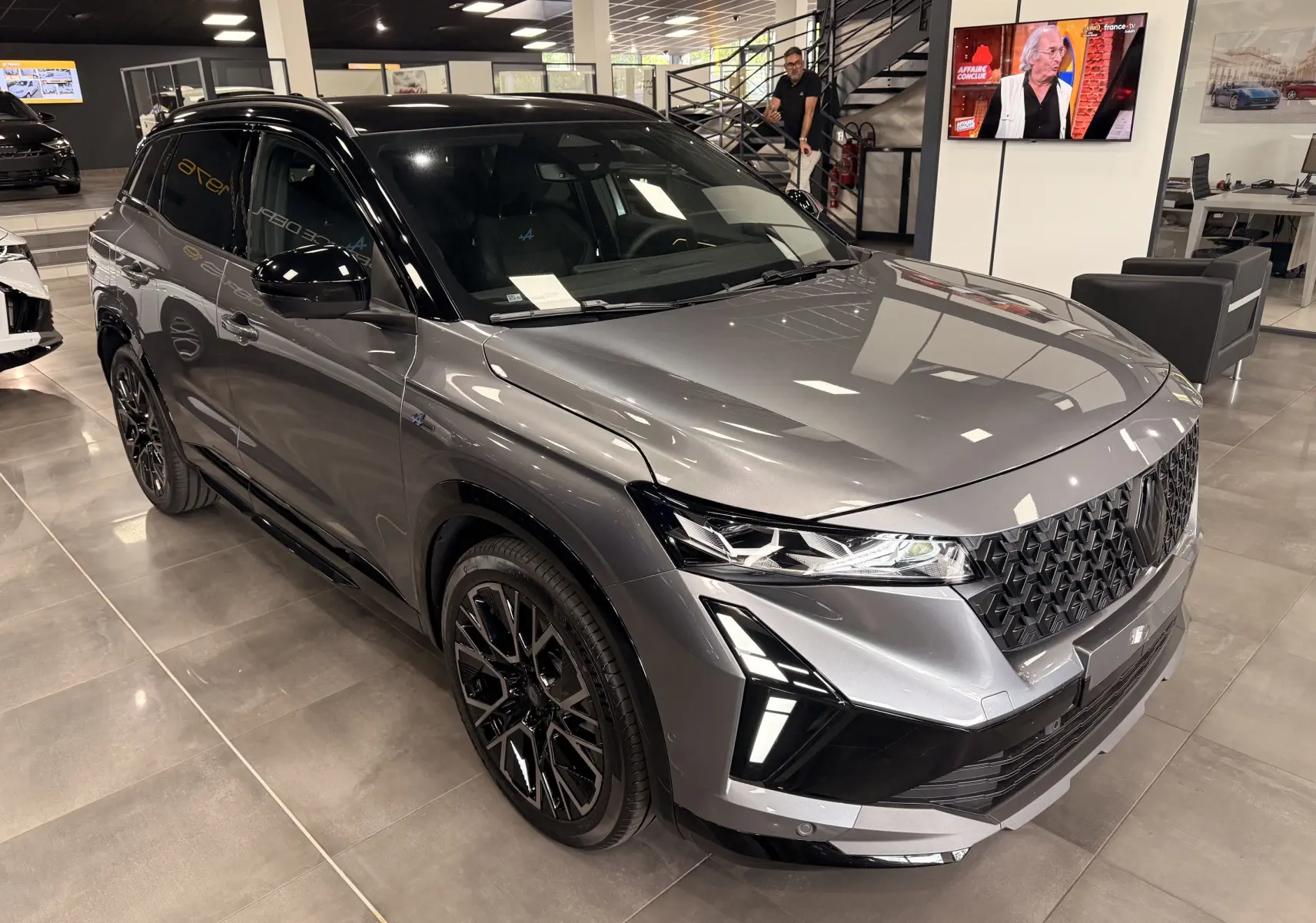 Renault Austral full hybrid gris schiste toit noir, vue 3/4 avant avec calandre noire et jantes noires en showroom.