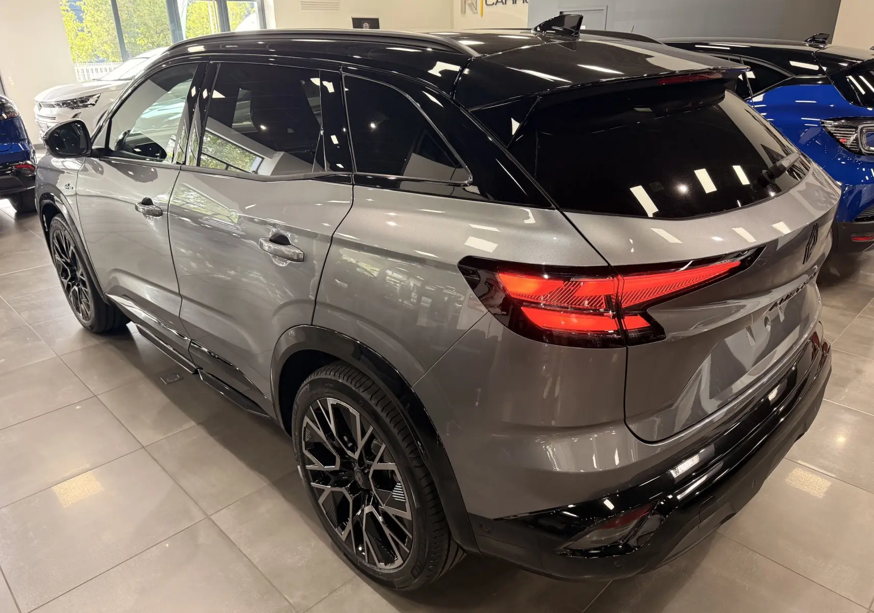 Vue 3/4 arrière droite du Renault Austral full hybrid gris schiste avec toit noir et jantes noires en concession.