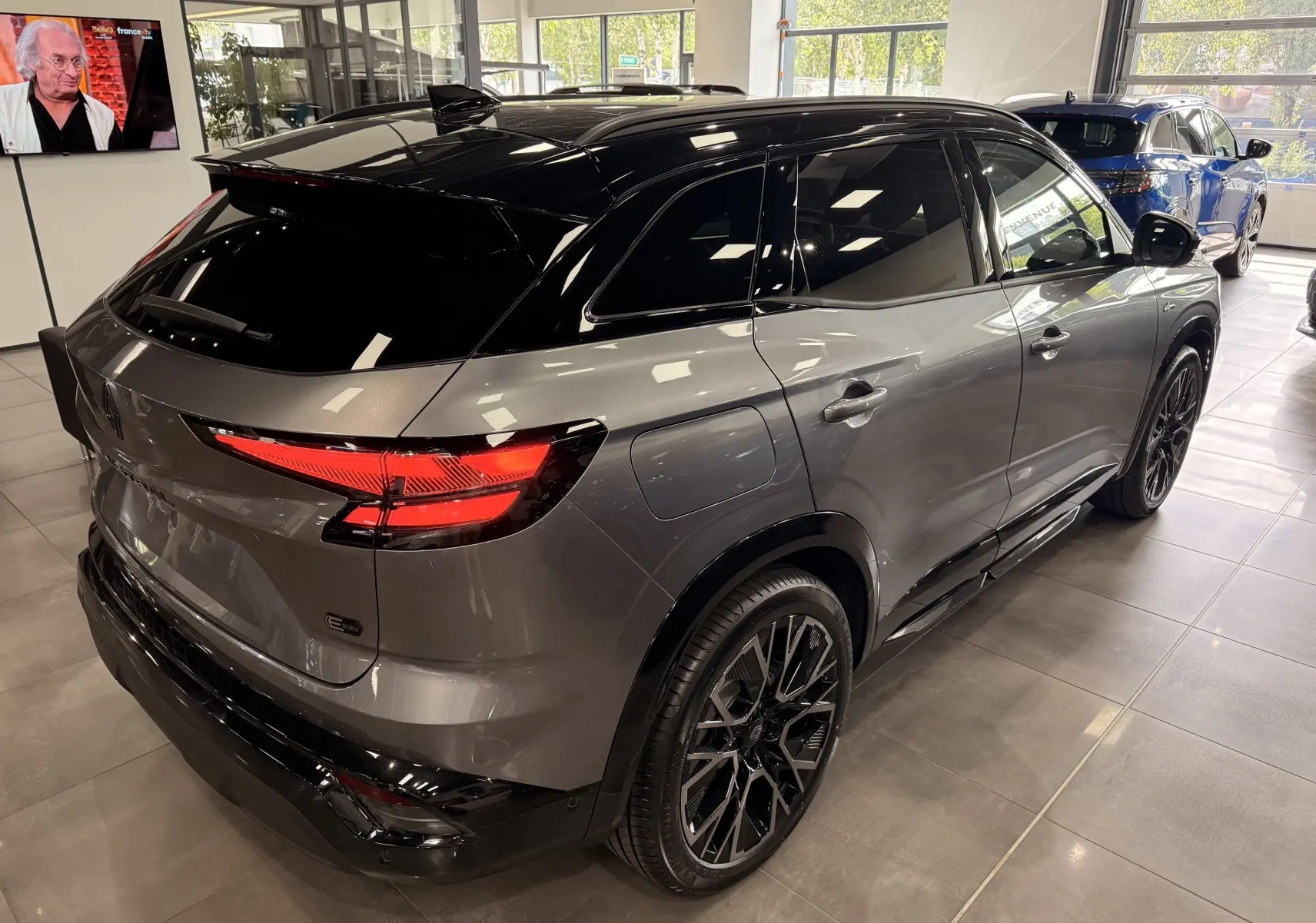 Renault Austral full hybrid gris schiste toit noir, vue 3/4 arrière droit en intérieur showroom.