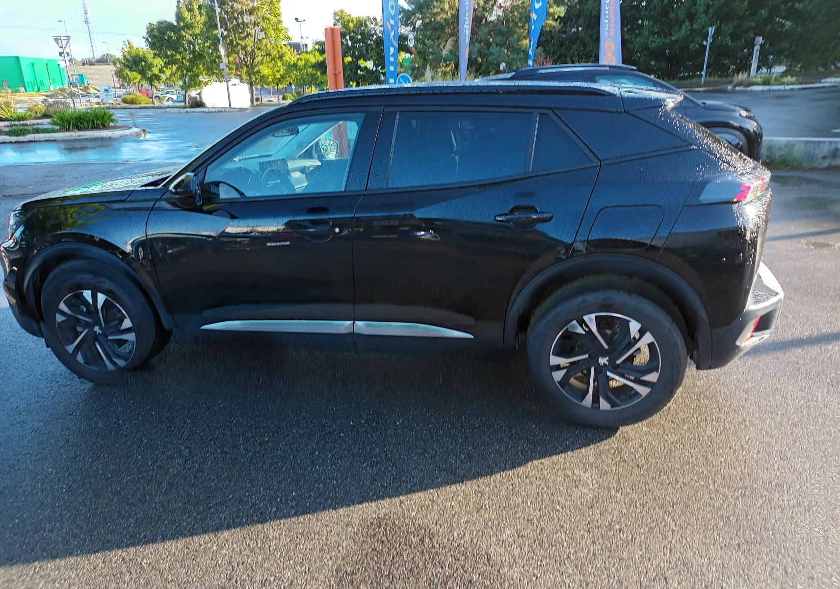 Peugeot 2008 noir vue de profil côté gauche, avec jantes biton et lignes modernes sous la lumière du matin.