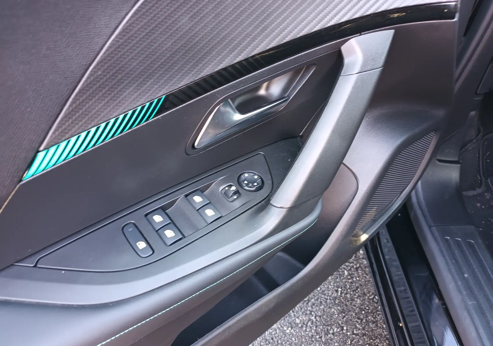 Détail de la porte côté conducteur du Peugeot 2008 noir 2022, montrant les commandes des vitres et la poignée intérieure.