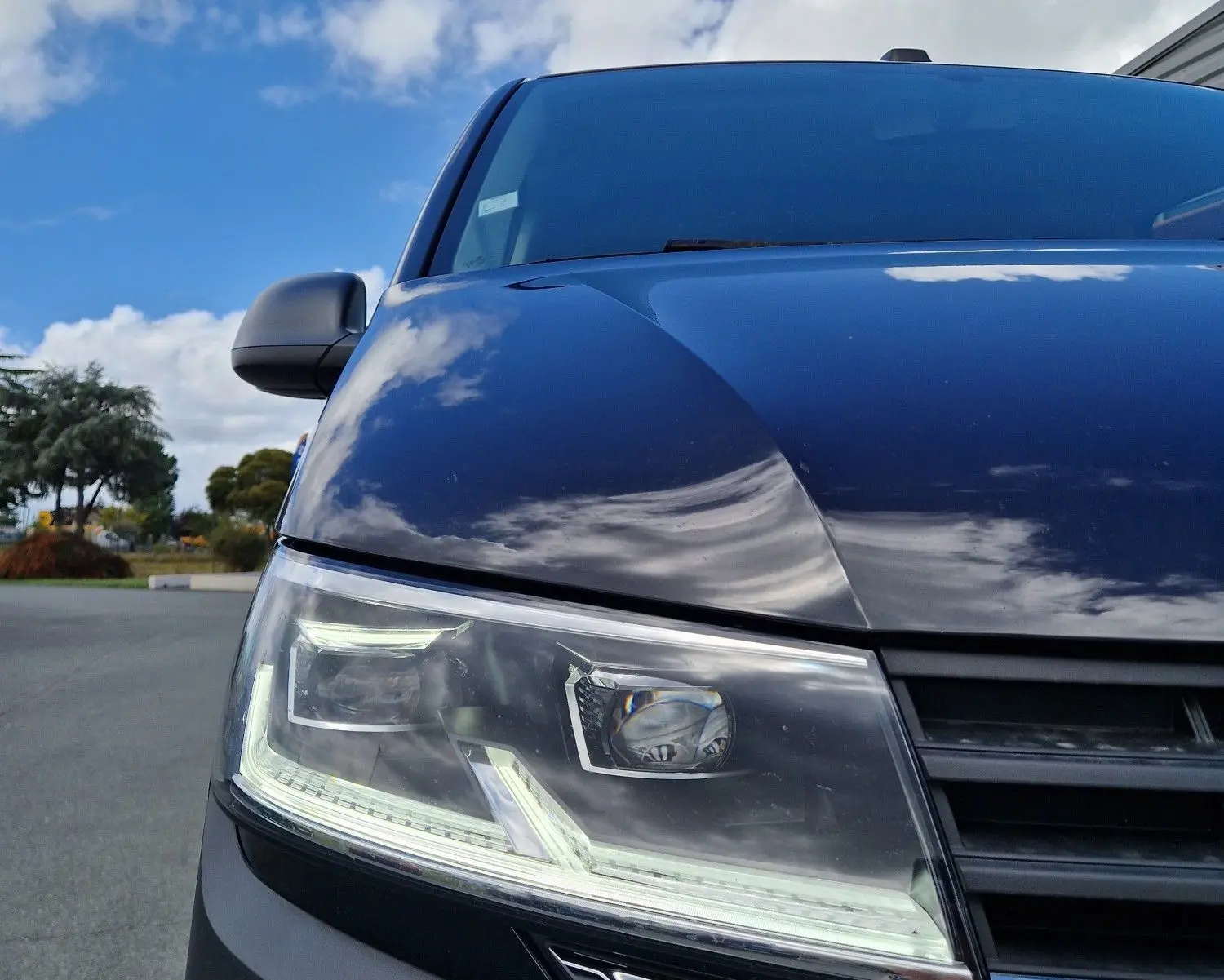 Gros plan sur l'avant droit du Volkswagen Transporter noir 2020, mettant en valeur son projecteur LED et la calandre.