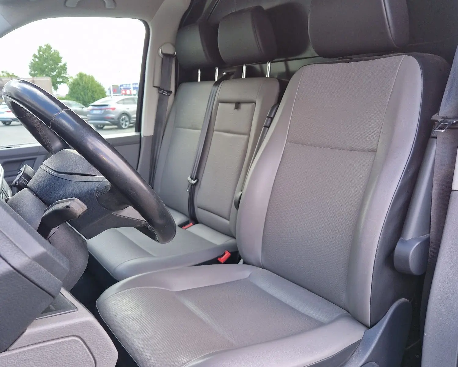 Vue intérieure côté conducteur du Volkswagen Transporter 2.0 TDi 2020 avec sièges gris et volant multifonction noir.