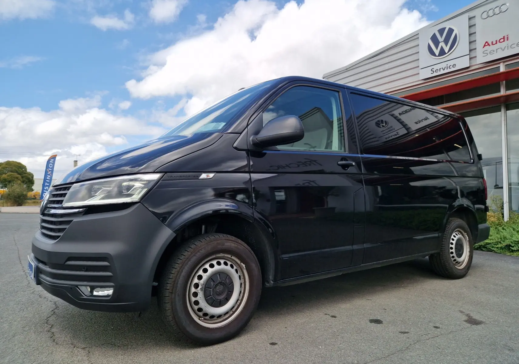 Vue 3/4 avant gauche d'un Volkswagen Transporter noir avec projecteurs LED et calandre noire mate.