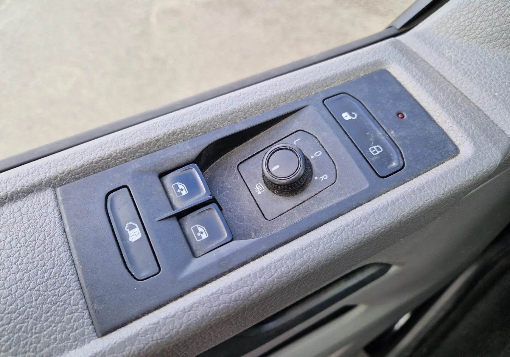 Gros plan sur les commandes de réglage des rétroviseurs et des vitres côté conducteur du Volkswagen Transporter noir 2020 finition Business Line.