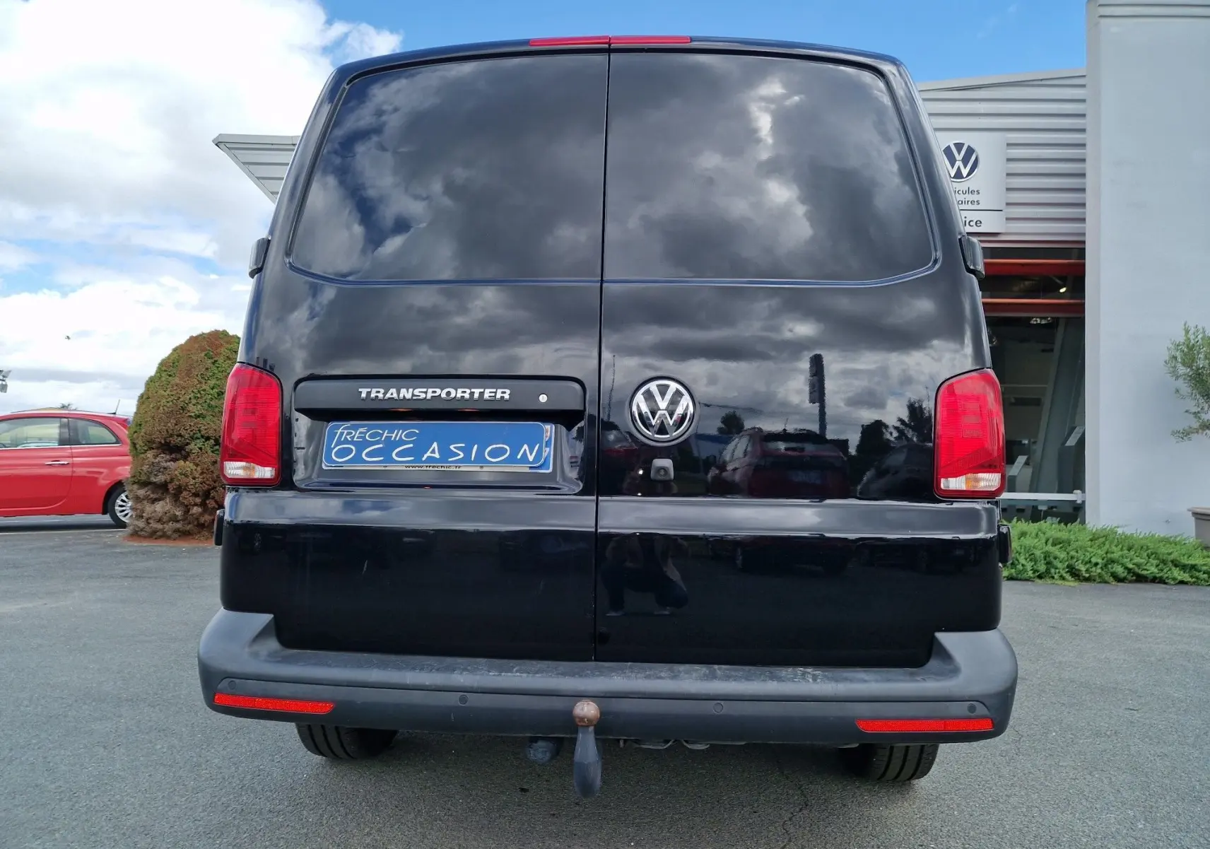 Vue arrière d'un Volkswagen Transporter noir 2020 avec attelage rigide et feux arrière rouges visibles.
