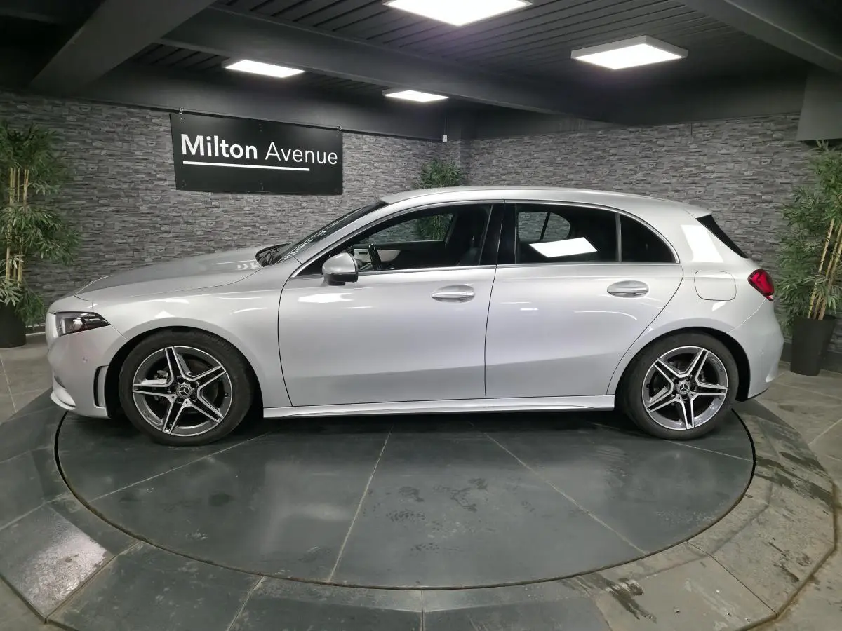 Profil côté gauche d'une Mercedes Classe A 200 d AMG Line gris métallisé avec jantes AMG 18 pouces en intérieur showroom.