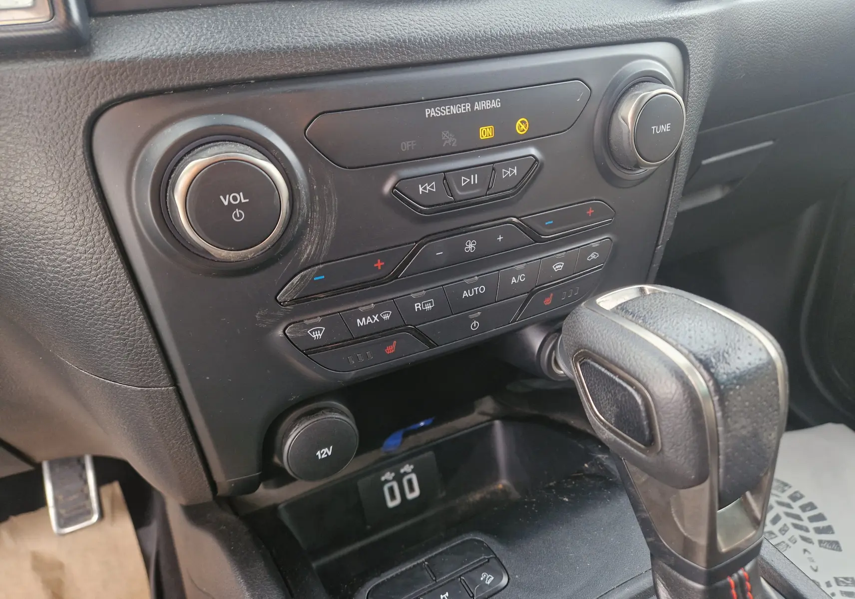 Vue rapprochée du tableau de bord et levier de vitesse du Ford Ranger Raptor 2022, finition noire avec commandes climatisation et audio.