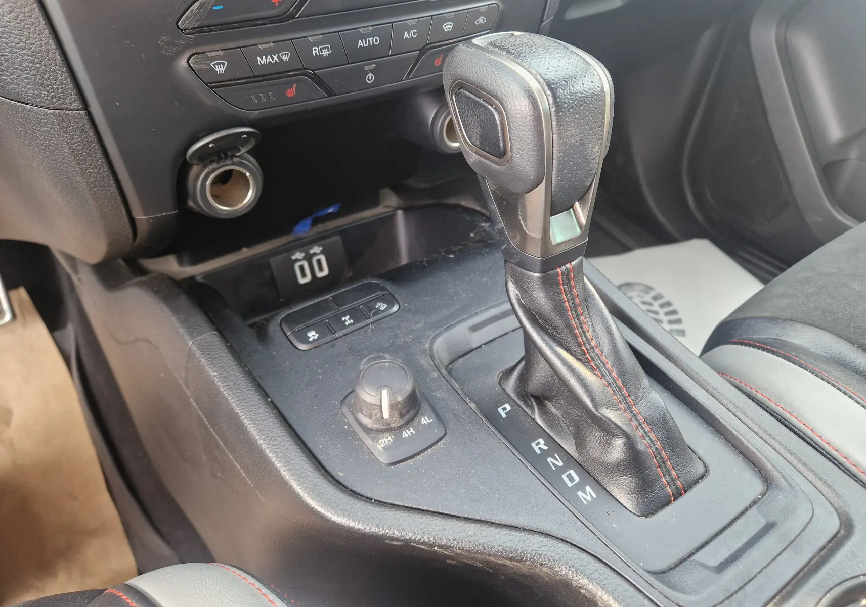 Le levier de vitesses automatique noir avec surpiqûres rouges du Ford Ranger Raptor 2022, vue intérieure centrée sur la console.