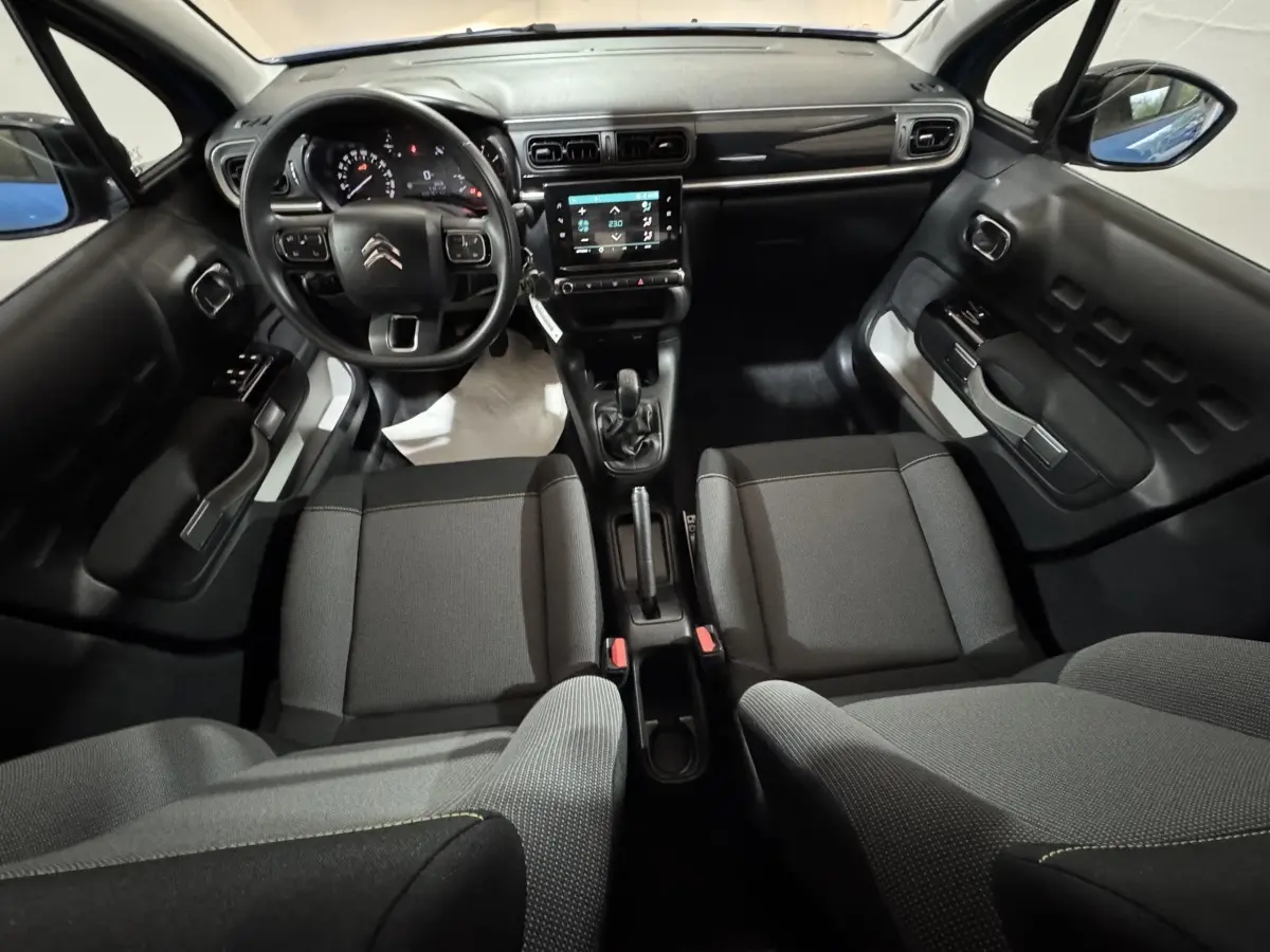 Vue intérieure avant de la Citroën C3 2018 avec tableau de bord noir, écran tactile central et sièges gris.