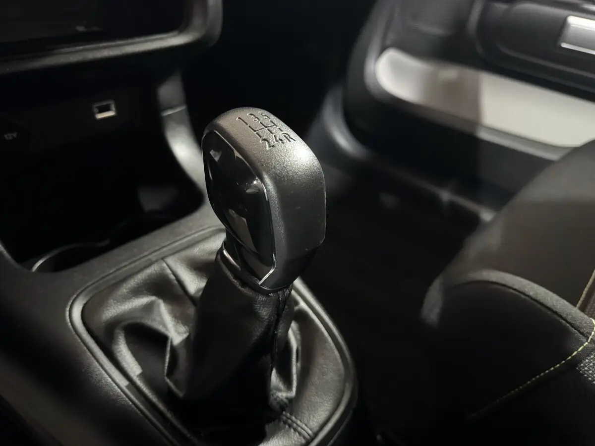 Le levier de vitesses manuel noir de la Citroën C3 PureTech 82 vu en gros plan côté conducteur.