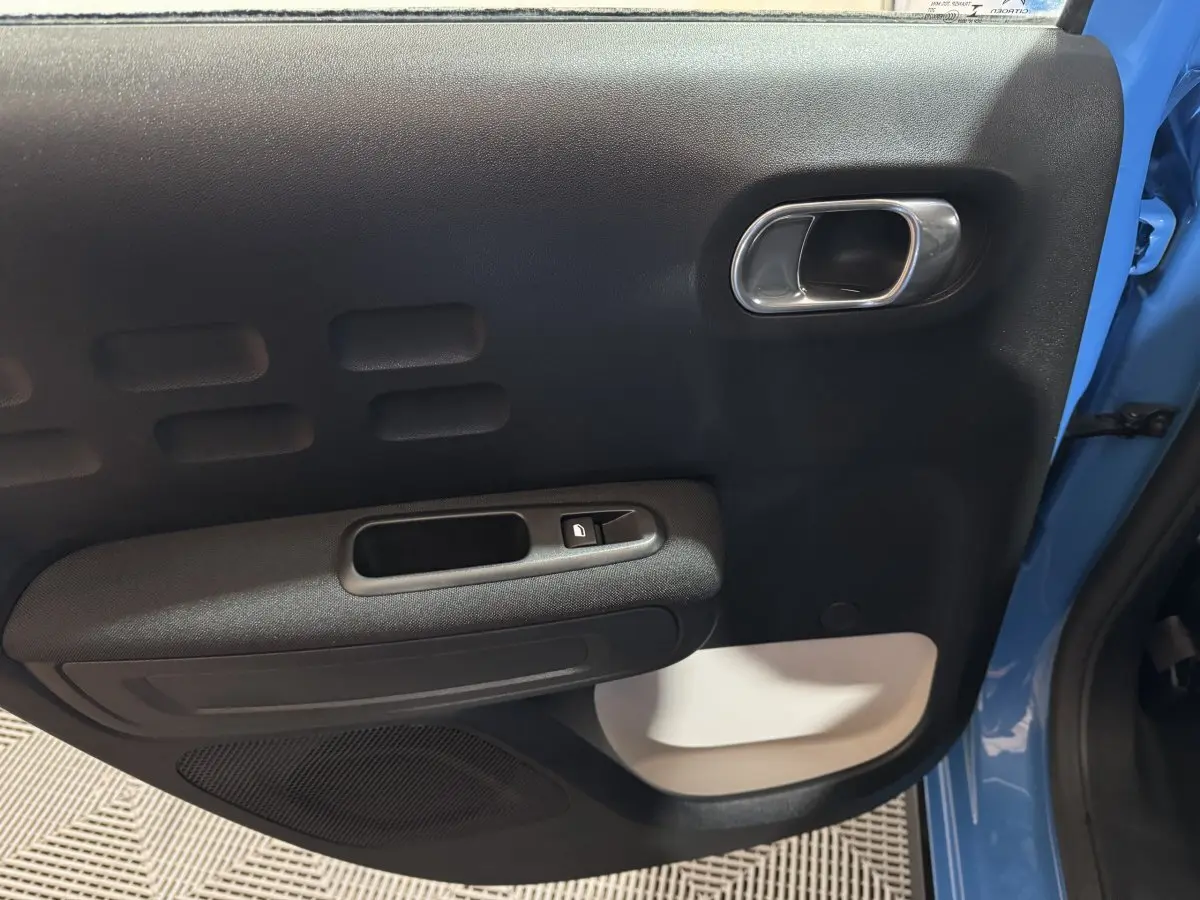 Gros plan sur la porte avant gauche bleu clair d'une Citroën C3 2018 avec poignée argentée et bouton de verrouillage.