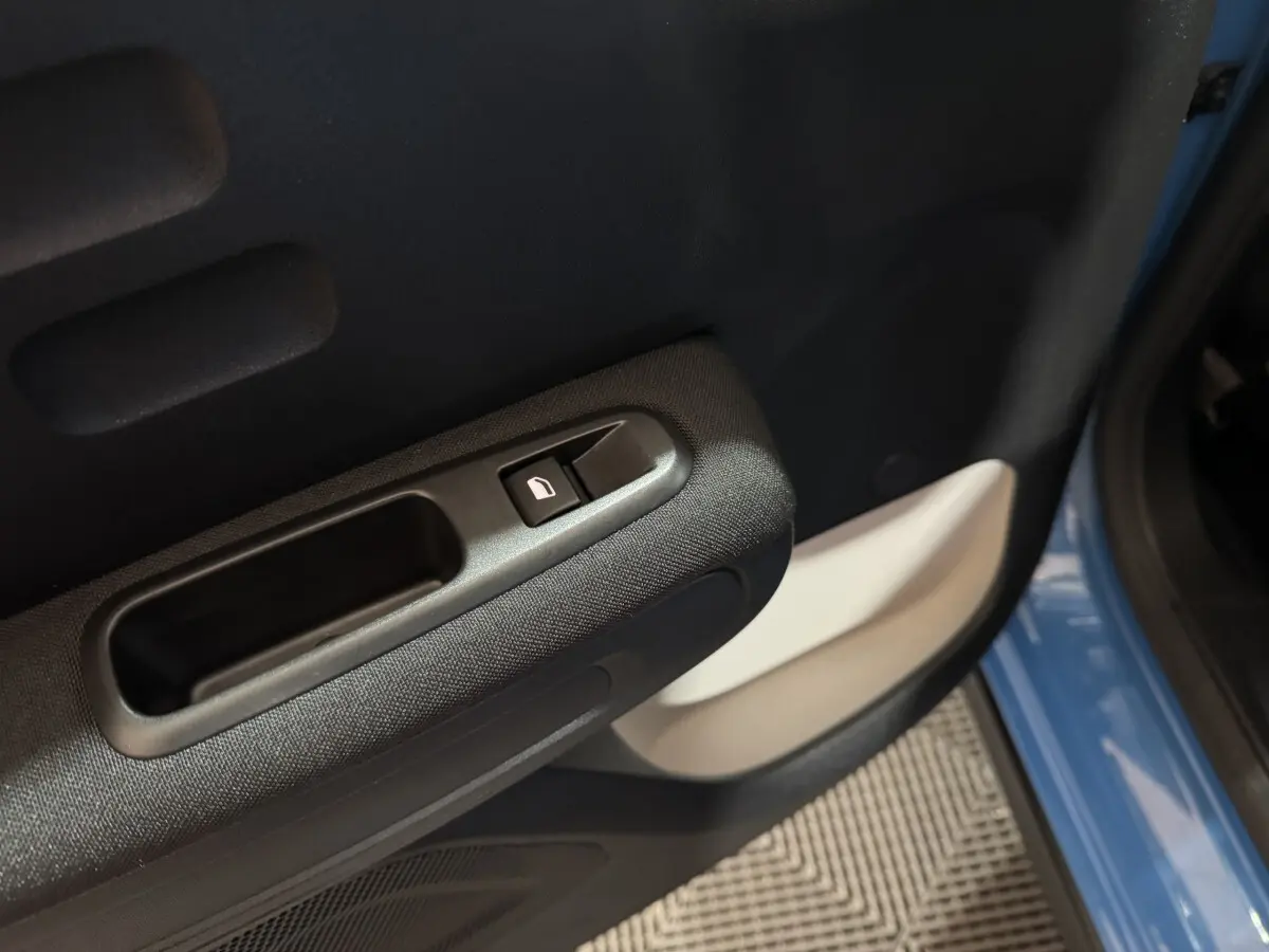 Gros plan sur la poignée intérieure et le bouton de verrouillage de la porte côté gauche d'une Citroën C3 bleu 2018.