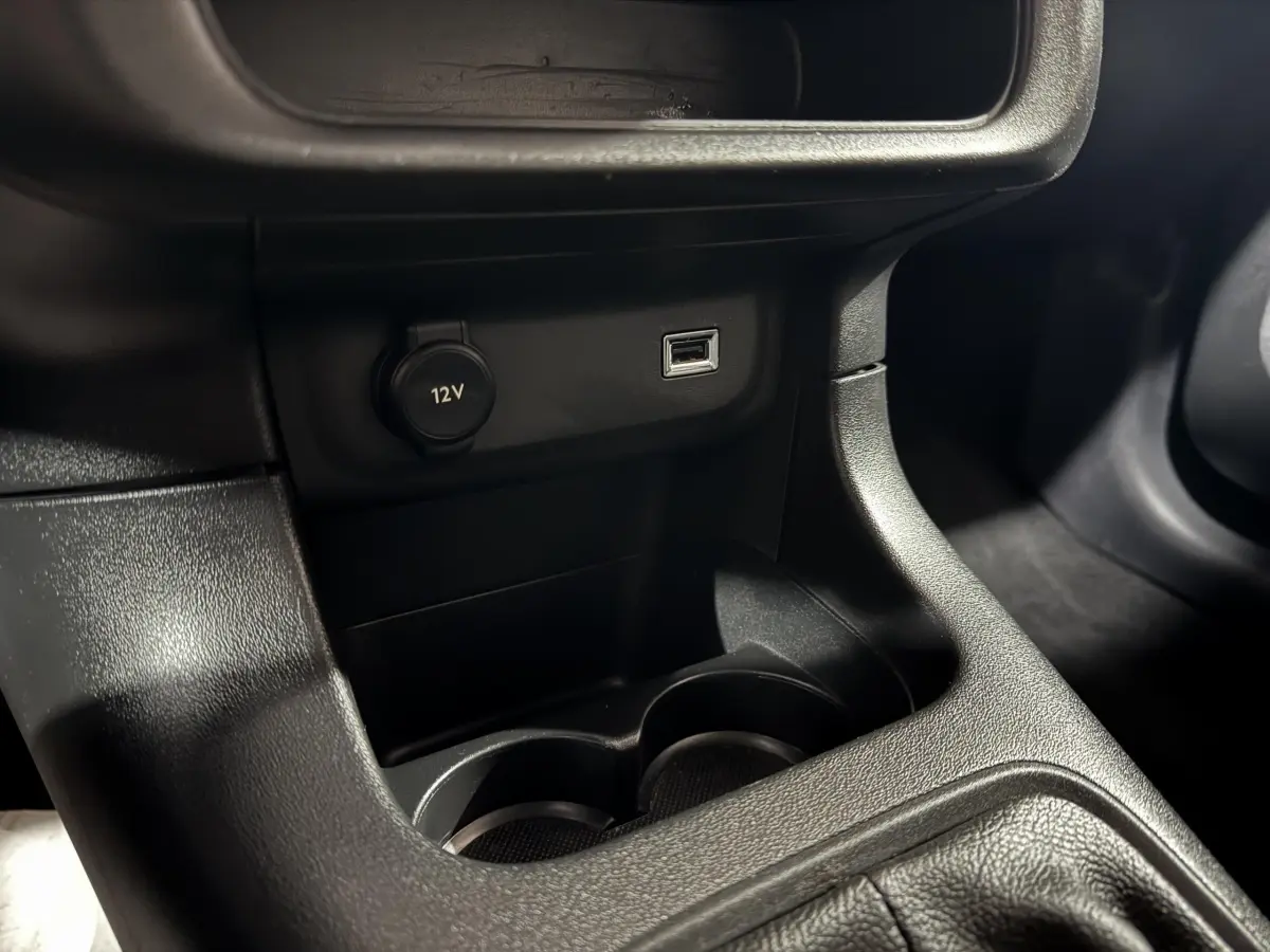 Prise 12V et port USB en gros plan sur la console centrale noire d'une Citroën C3 bleu 2018.