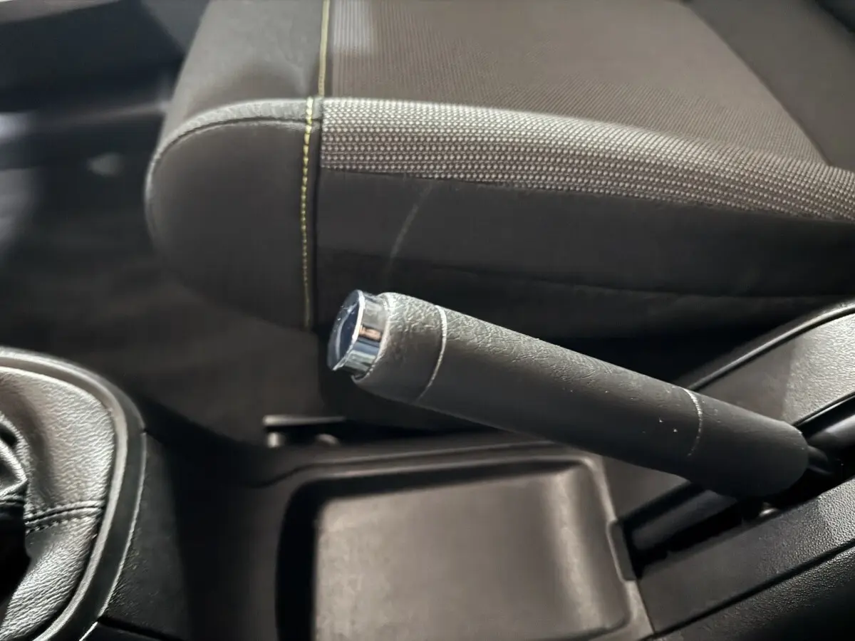 Gros plan sur le frein à main en cuir noir et la console centrale d'une Citroën C3 2018, intérieur sombre.