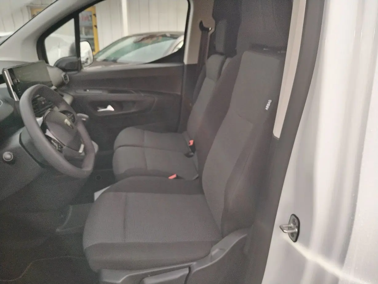 Vue intérieure côté conducteur du Peugeot Partner Fourgon blanc Icy 2025, montrant les sièges avant et le volant.
