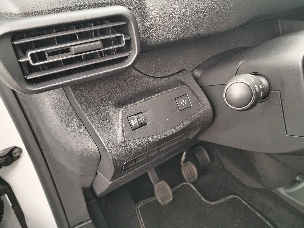 Détail intérieur côté gauche du tableau de bord du Peugeot Partner Fourgon blanc, avec commandes et pédales visibles.