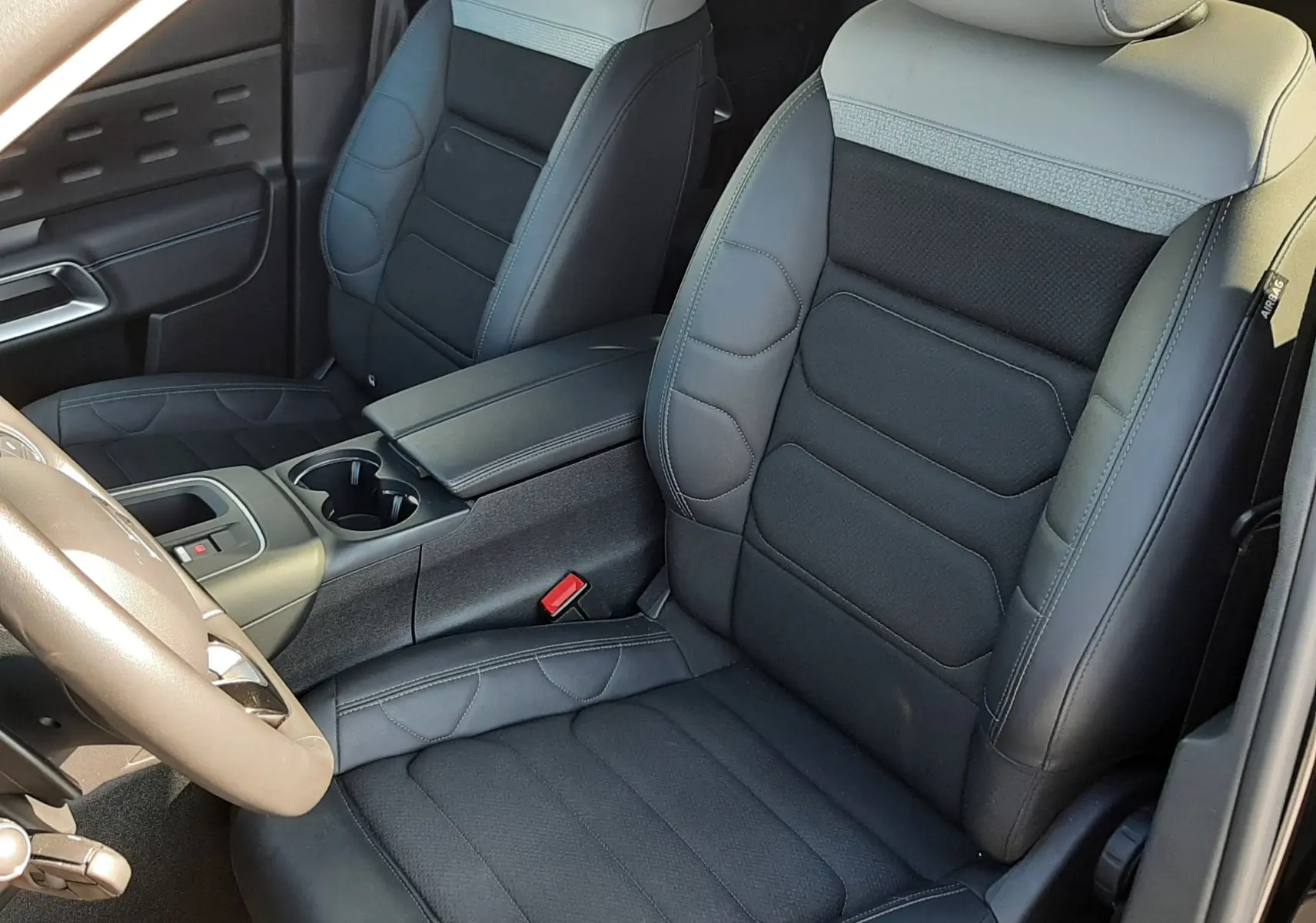 Vue intérieure côté conducteur du Citroën C5 Aircross 2024, sièges bi-matière gris clair et noir avec console centrale.