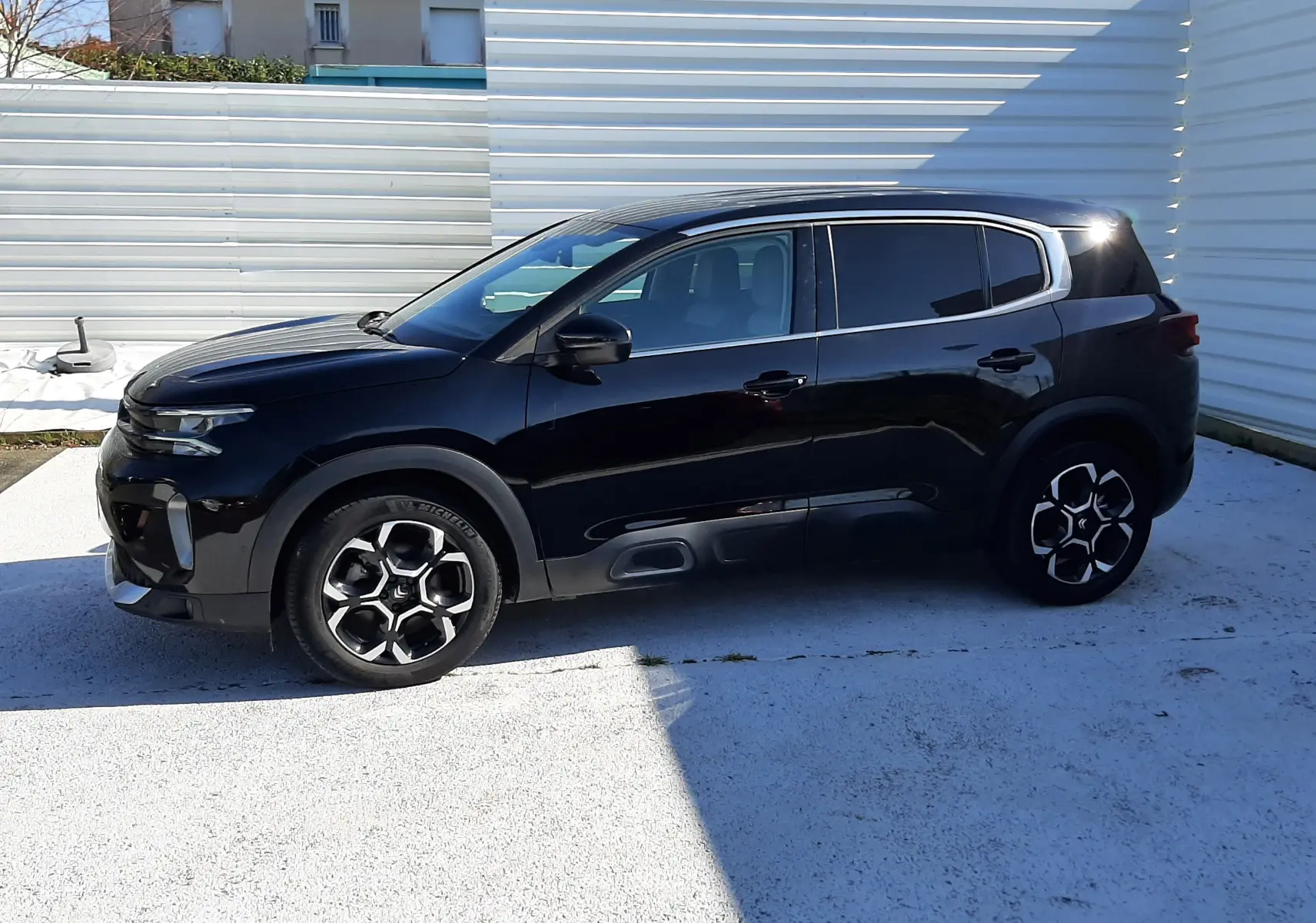 Vue de profil côté gauche d'un Citroën C5 Aircross noir Perla Nera 2024, avec jantes biton et vitres teintées.