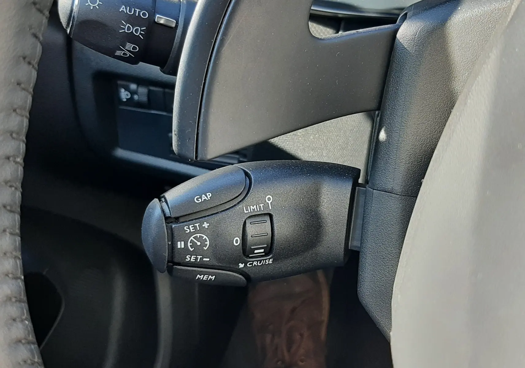 Gros plan sur la commande de régulateur de vitesse à gauche du volant d’un Citroën C5 Aircross 2024 noir Perla Nera.