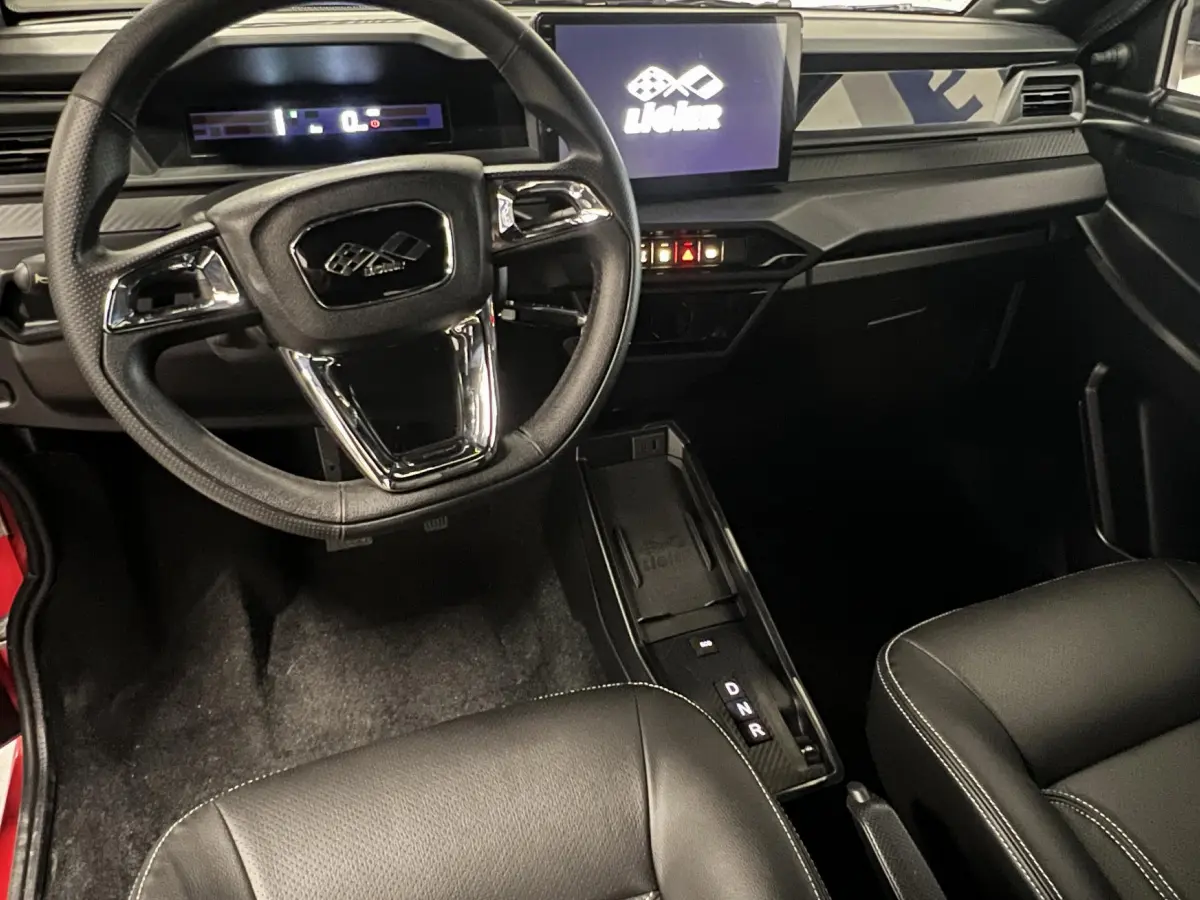 Vue intérieure avant du tableau de bord et volant noir du LIGIER JS50 BEV 8KWH ELITE avec écran tactile central allumé.