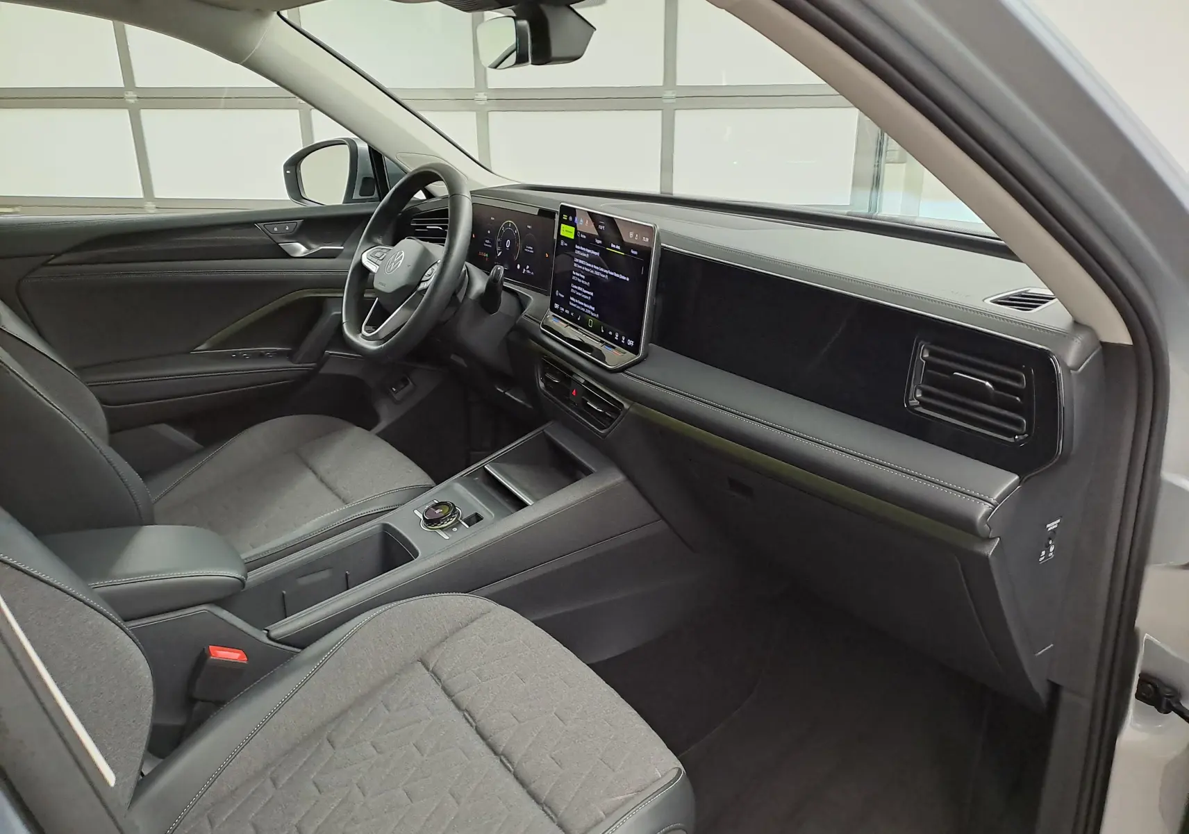 Vue intérieure côté conducteur du Volkswagen Tiguan 2025 avec tableau de bord moderne et sièges tissu gris.