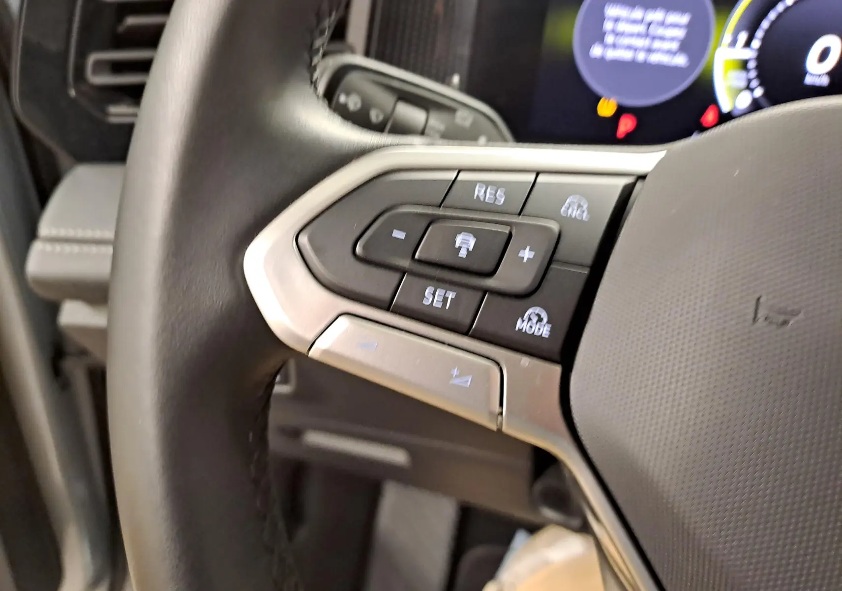Gros plan sur les commandes au volant côté gauche du Volkswagen Tiguan 2025, cuir noir avec finitions argentées.