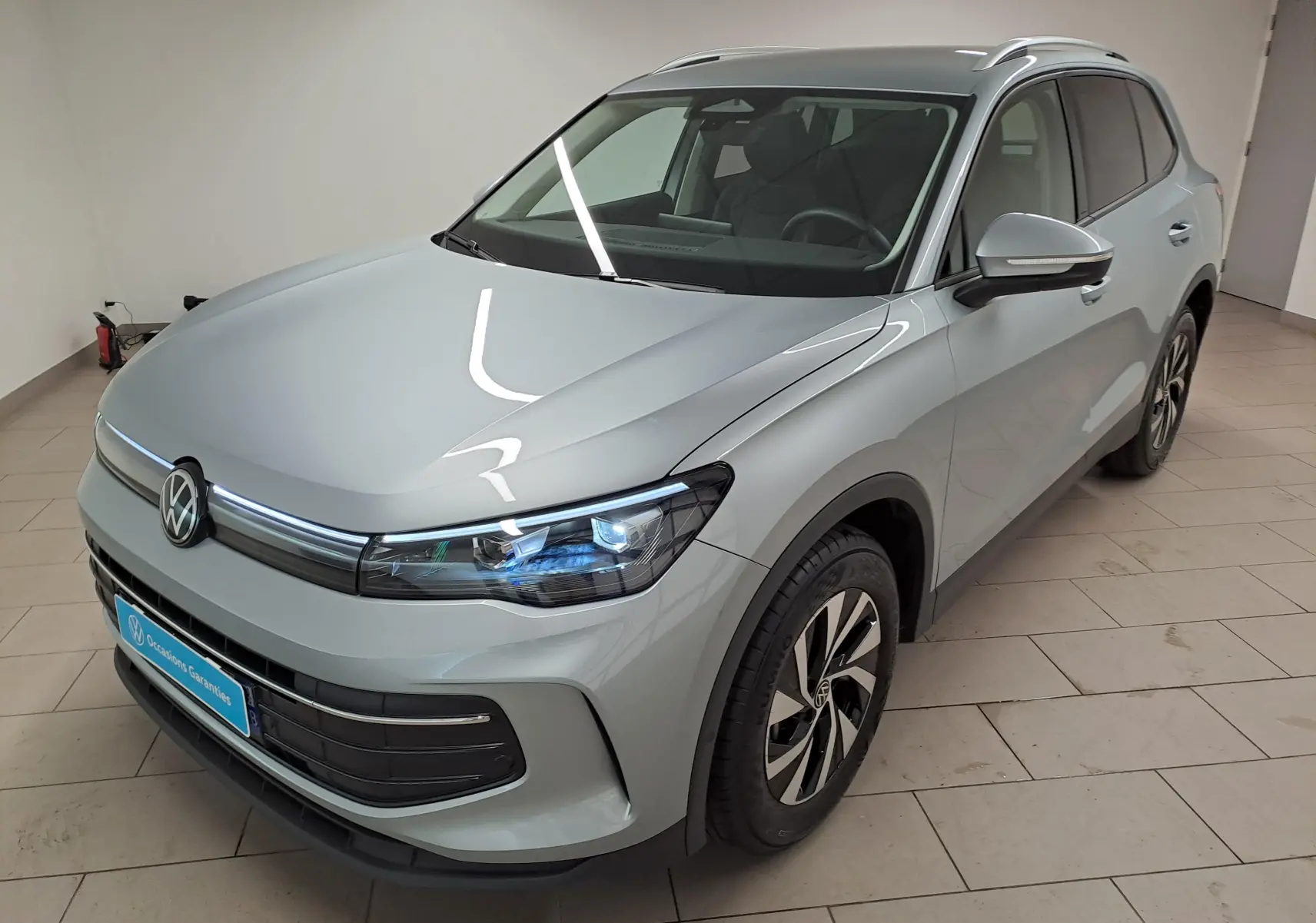 Vue 3/4 avant droit du Volkswagen Tiguan 2.0 TDI 150 DSG7 en argent Dolomite avec phares LED et jantes alliage.