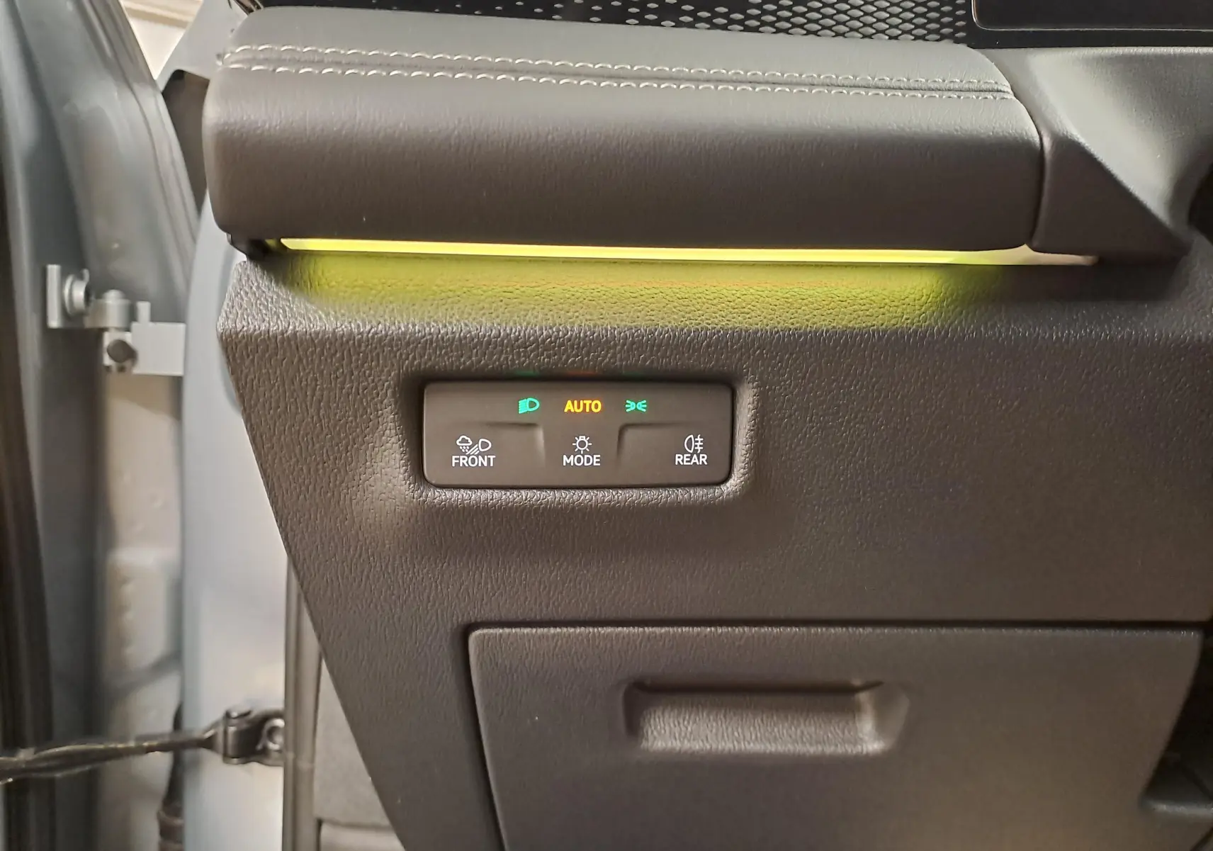 Détail du tableau de bord côté gauche du Volkswagen Tiguan 2025 Argent Dolomite avec commandes d'éclairage et bandeau lumineux jaune.