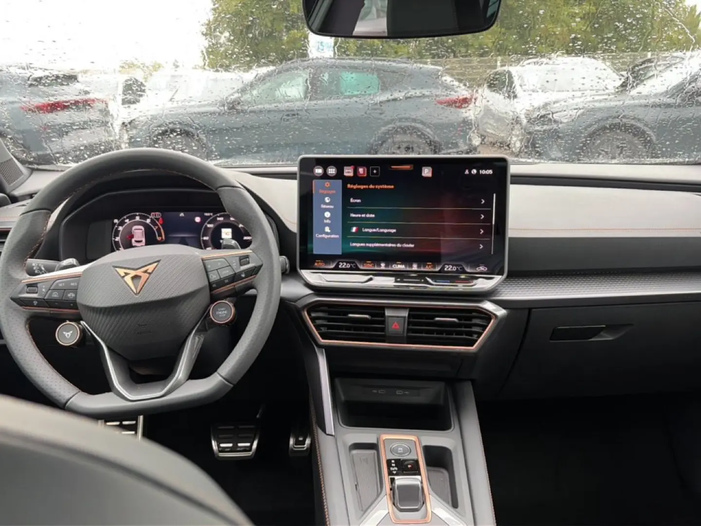 Vue intérieure du tableau de bord et volant multifonction du CUPRA Formentor 1.5 etsi hybrid 2026, avec écran tactile et pluie sur le pare-brise.