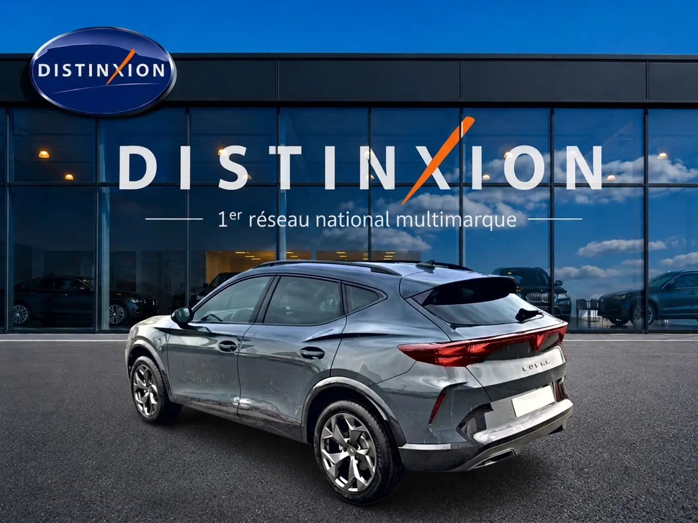 Vue 3/4 arrière droite d'une CUPRA Formentor bleu fjord avec feux arrière LED et jantes 18 pouces devant un showroom Distinxion.