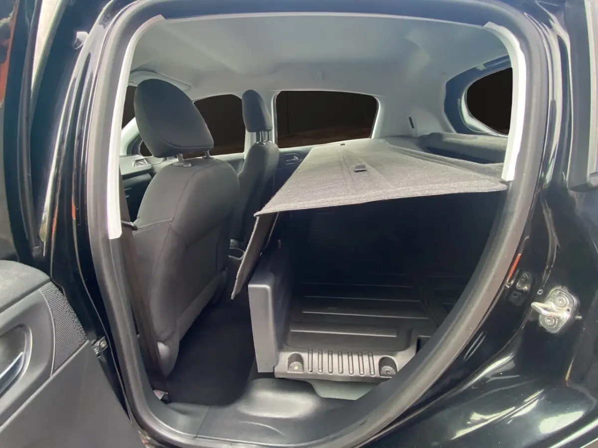 Vue intérieure côté droit de la Peugeot 208 Affaire noire, montrant les sièges avant et l’espace de chargement avec cloison partielle.
