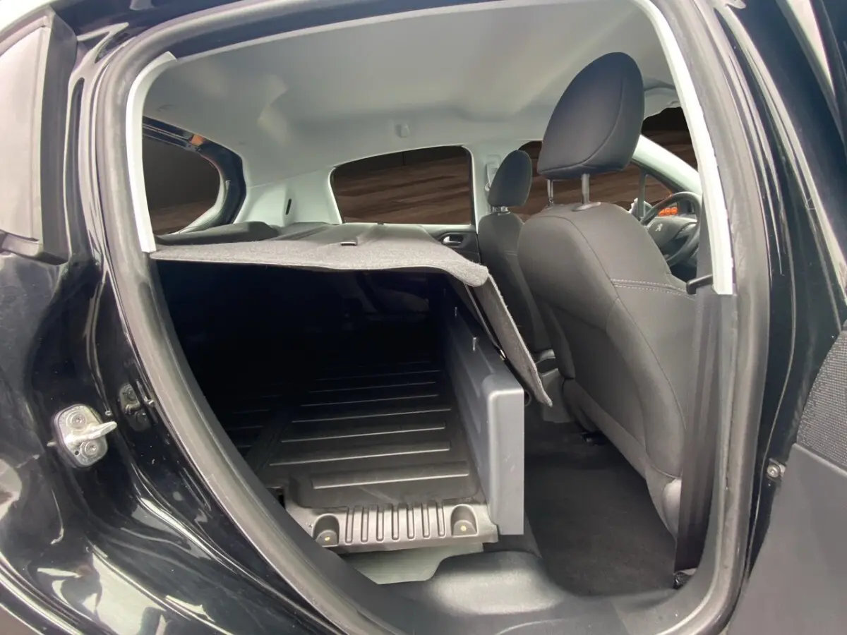 Vue intérieure côté droit d'un Peugeot 208 Affaire noir, montrant la cloison pleine et l'espace de chargement arrière.