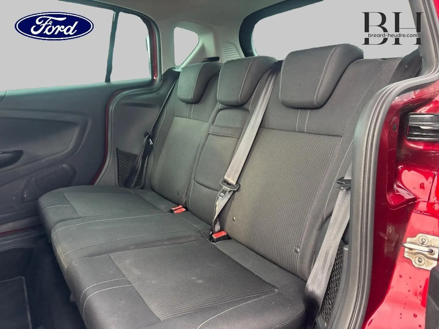 Vue intérieure sur la banquette arrière noire du Ford B-MAX rouge Premium avec porte latérale coulissante ouverte.