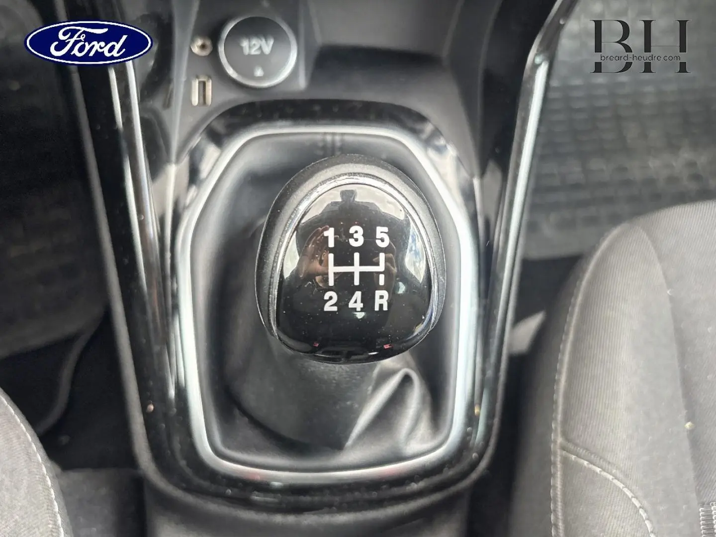 Le levier de vitesses manuel noir de la Ford B-MAX 2017, vue rapprochée de dessus avec sièges gris visibles.