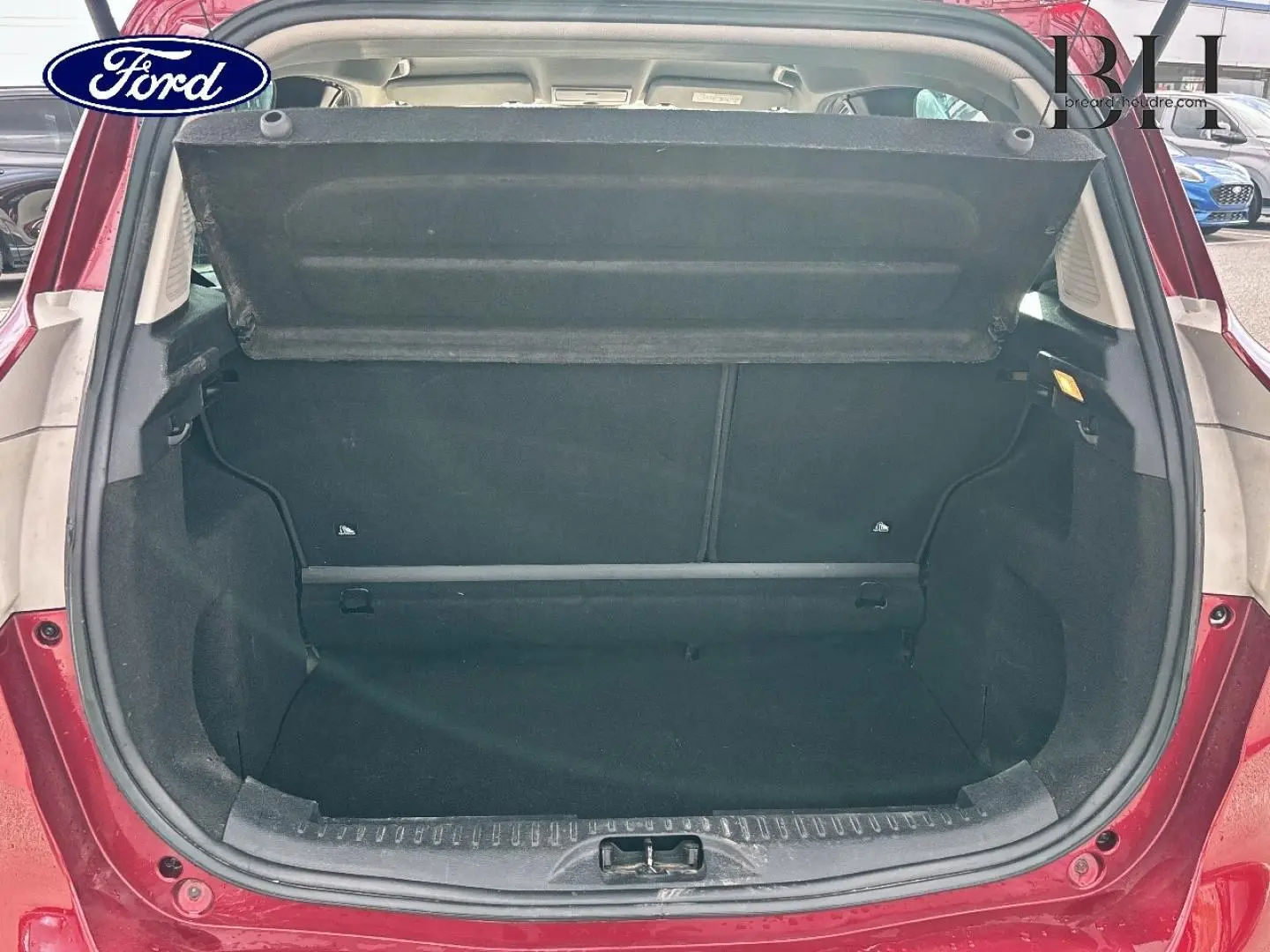 Coffre ouvert d'une Ford B-MAX 2017 rouge Premium Candy, vue arrière centrée montrant l'espace de chargement vide.