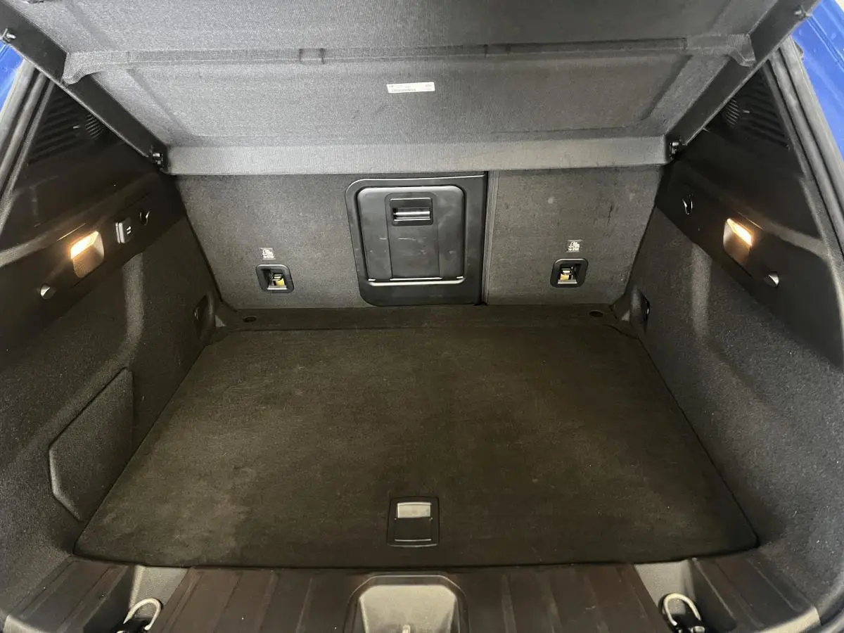 Coffre ouvert de l'Alfa Romeo Tonale bleu 2024, montrant un espace de chargement propre et éclairé.