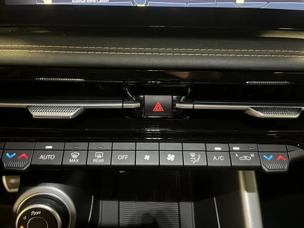 Tableau de bord noir avec commandes climatisation et bouton de warning rouge de l'Alfa Romeo Tonale Sprint 2024.