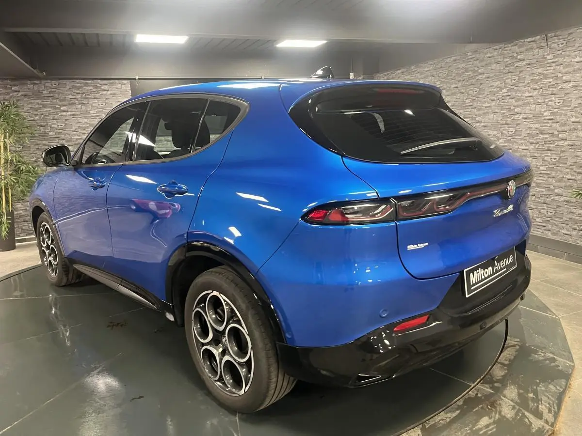 Vue 3/4 arrière droite d'un Alfa Romeo Tonale bleu métallisé avec jantes en alliage et feux arrière LED distinctifs.