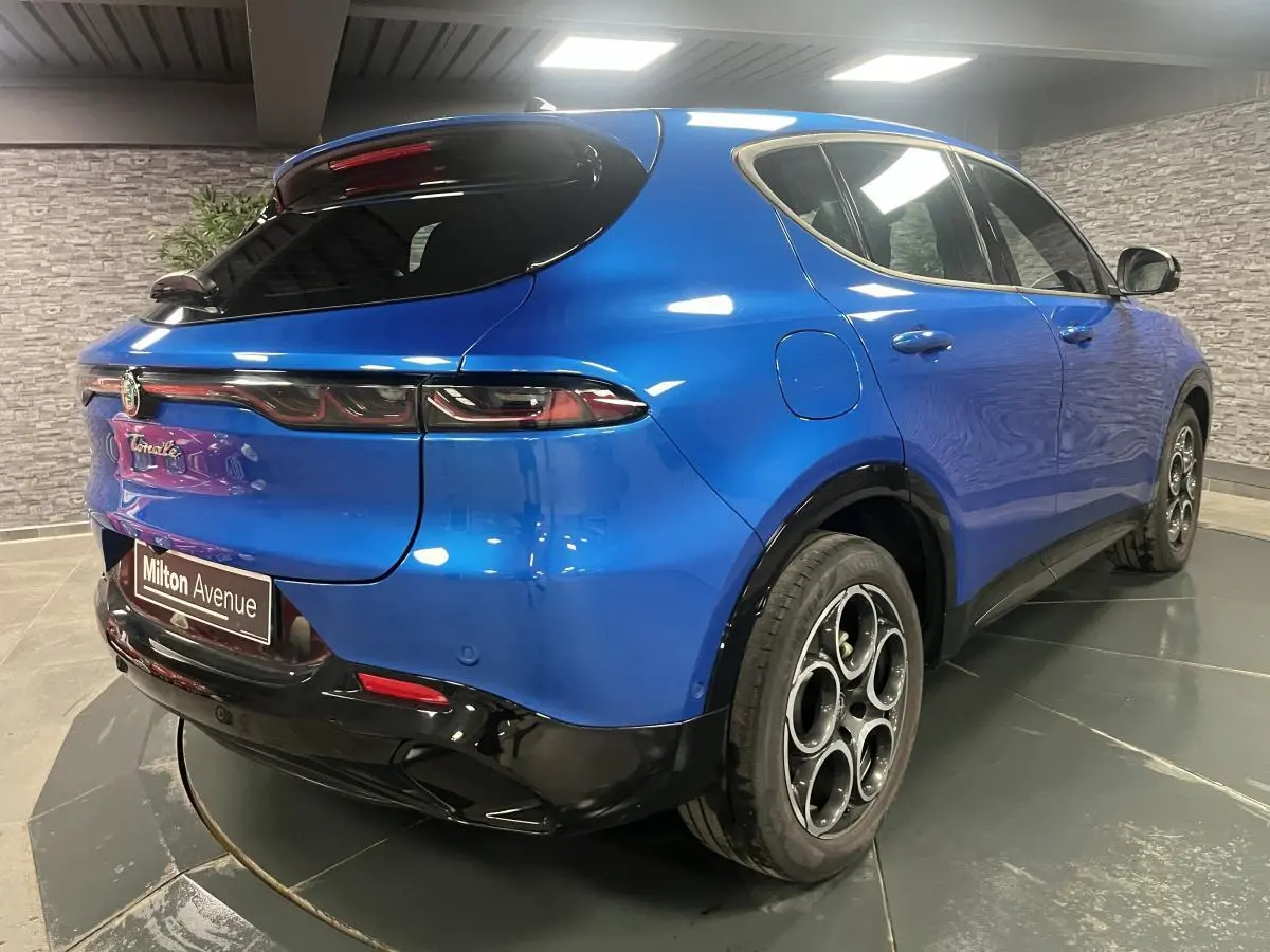 Vue 3/4 arrière droite de l'Alfa Romeo Tonale bleu métallisé avec jantes alliage et diffuseur noir brillant.