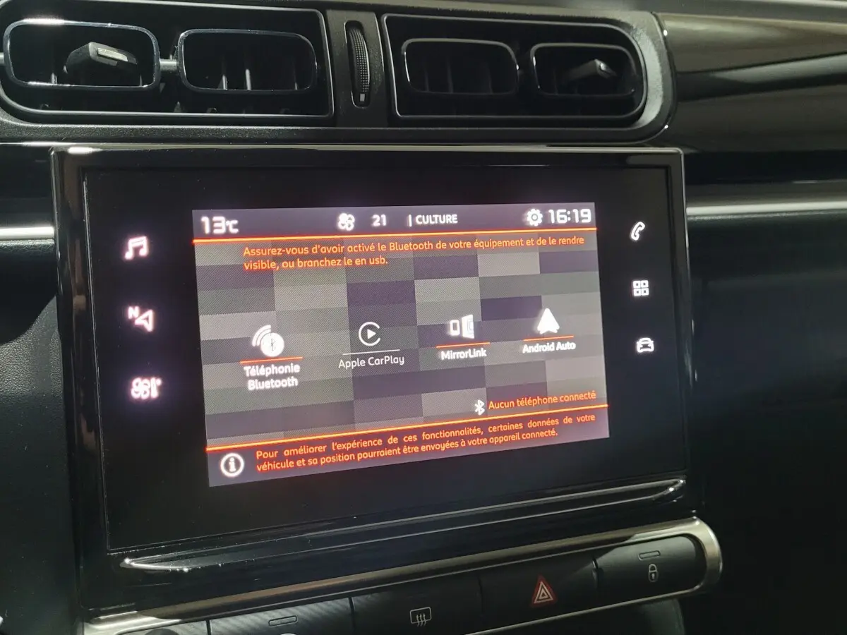Écran tactile central allumé dans l'habitacle d'une Citroën C3 beige, affichant les options connectivité.