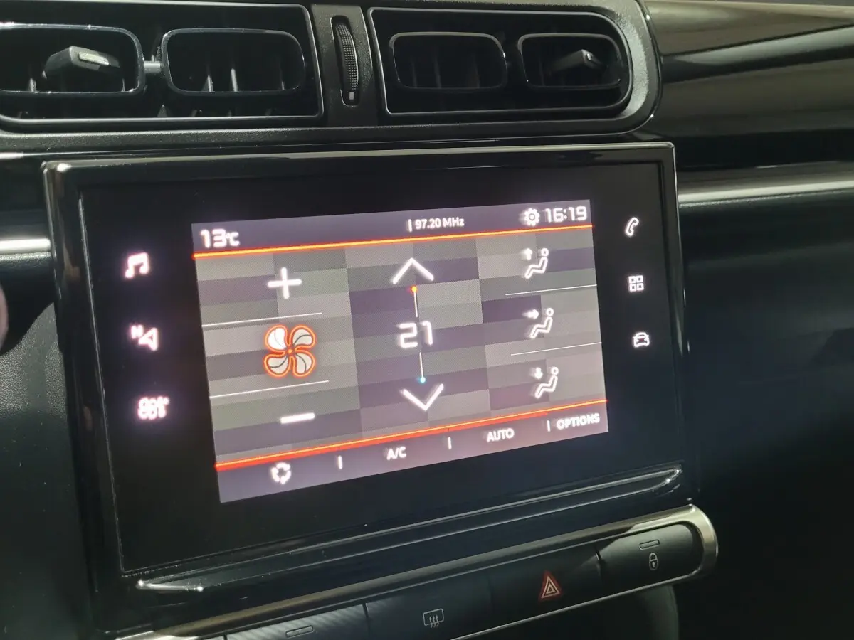 Écran tactile central affichant la climatisation à 21°C dans l'habitacle noir d'une Citroën C3 beige 2022.