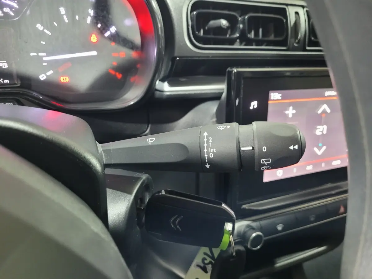 Gros plan sur la manette d'essuie-glace et le tableau de bord noir de la Citroën C3 beige 2022, écran tactile visible.