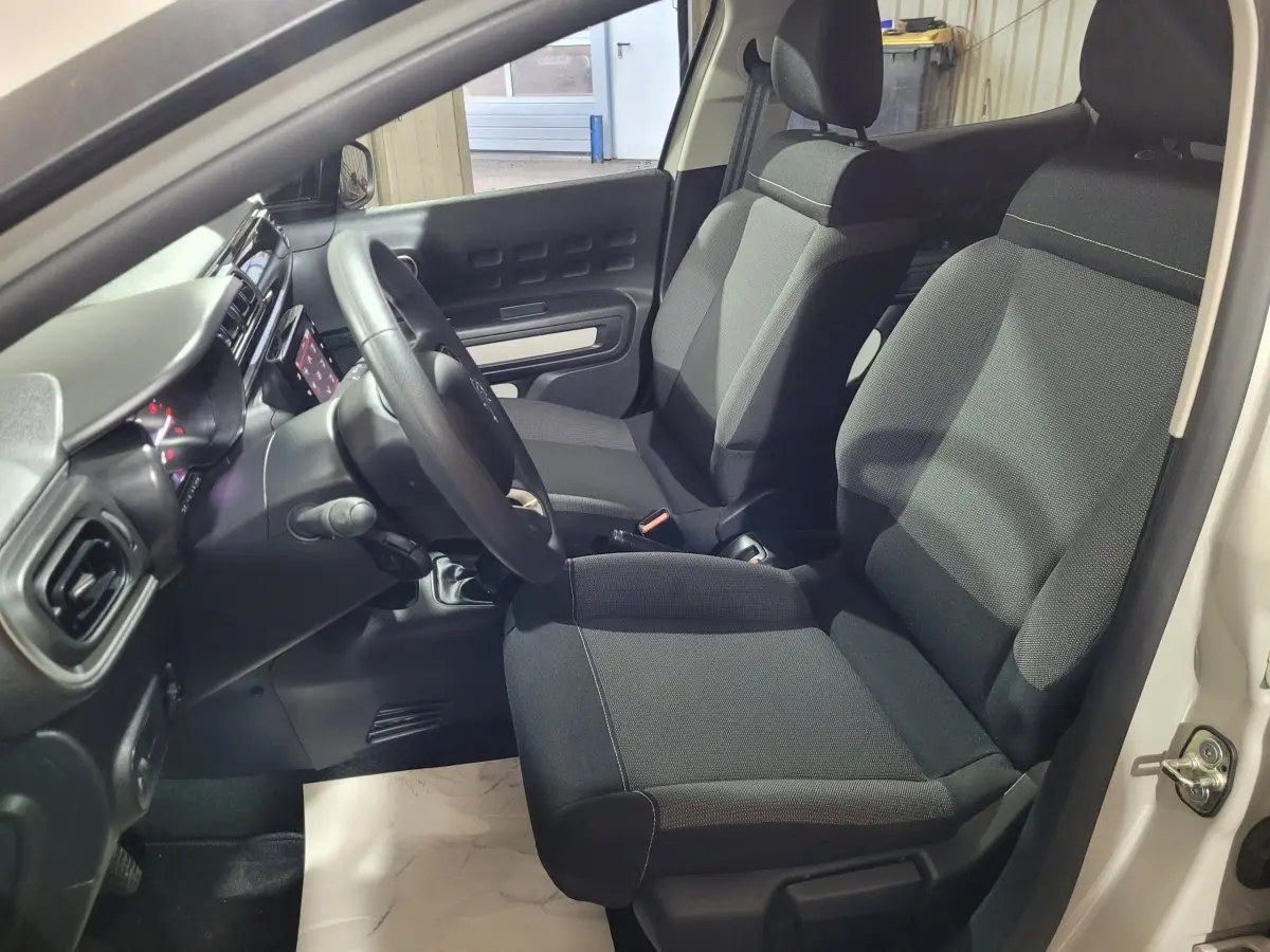 Vue intérieure côté conducteur de la Citroën C3 beige 2022, montrant sièges noirs et tableau de bord avec écran tactile.