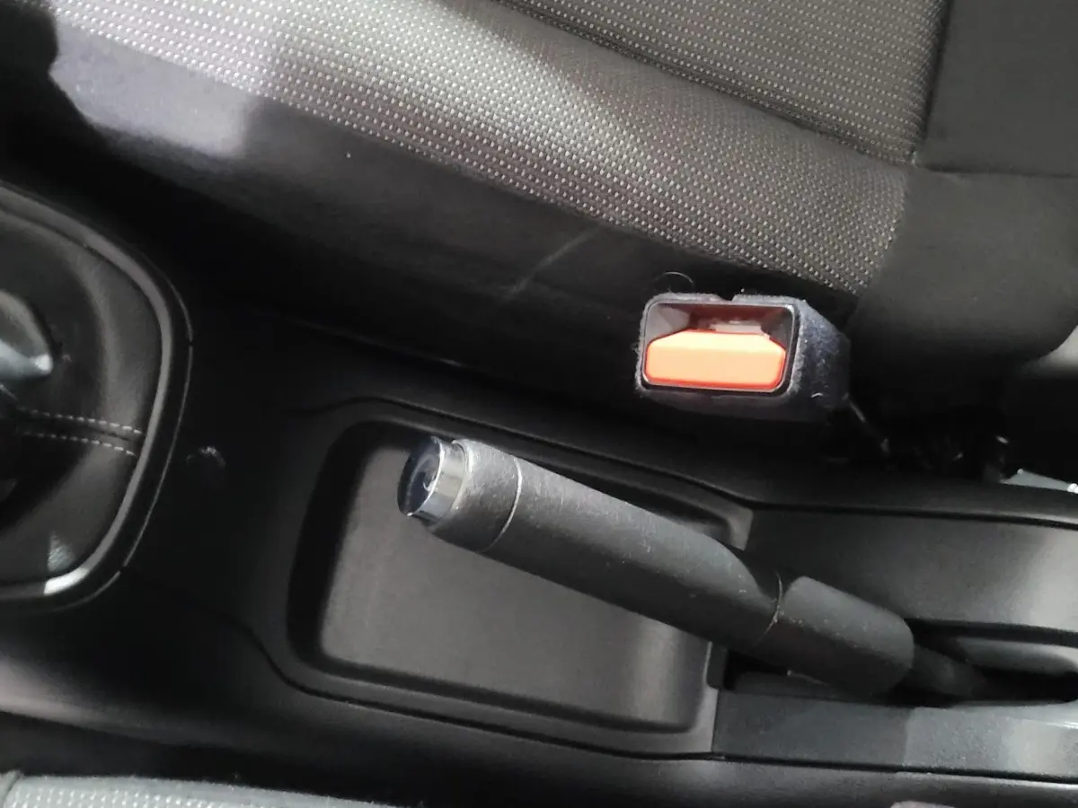 Gros plan sur le frein à main et la ceinture de sécurité côté conducteur dans l'habitacle d'une Citroën C3 beige.
