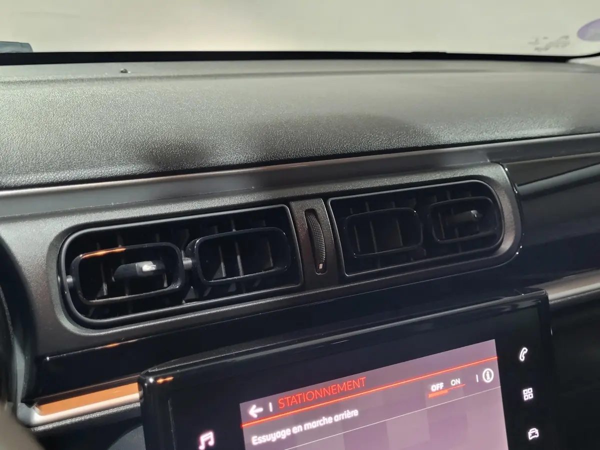 Gros plan sur la console centrale noire et les aérateurs du tableau de bord d'une Citroën C3 beige de 2022.