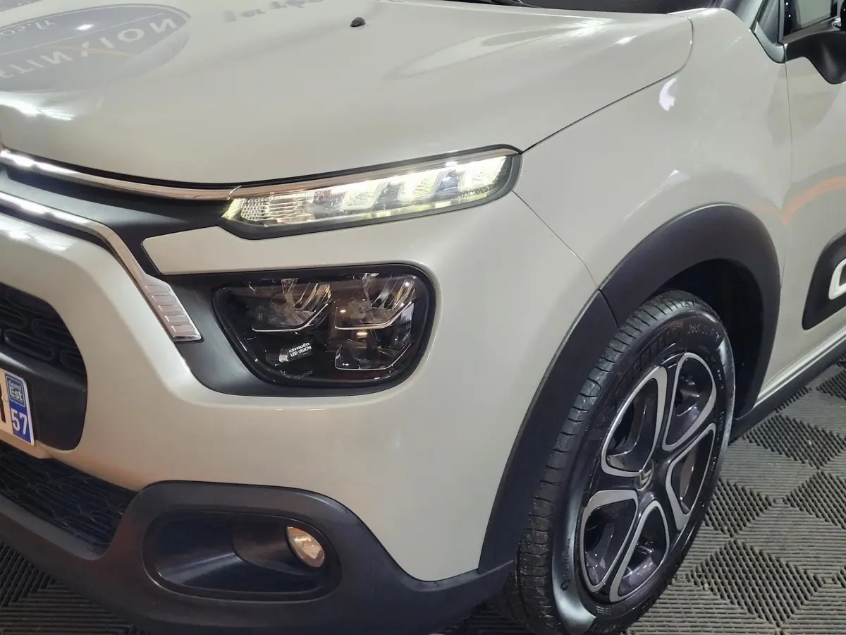 Vue 3/4 avant droit d'une Citroën C3 beige 2022 avec phares LED et jantes alliage distinctives.